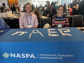 Two people sitting at a table with AER spelled out in pens