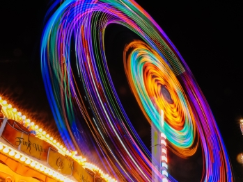 Time lapse of a ferris wheel at night creating circles of neon colors