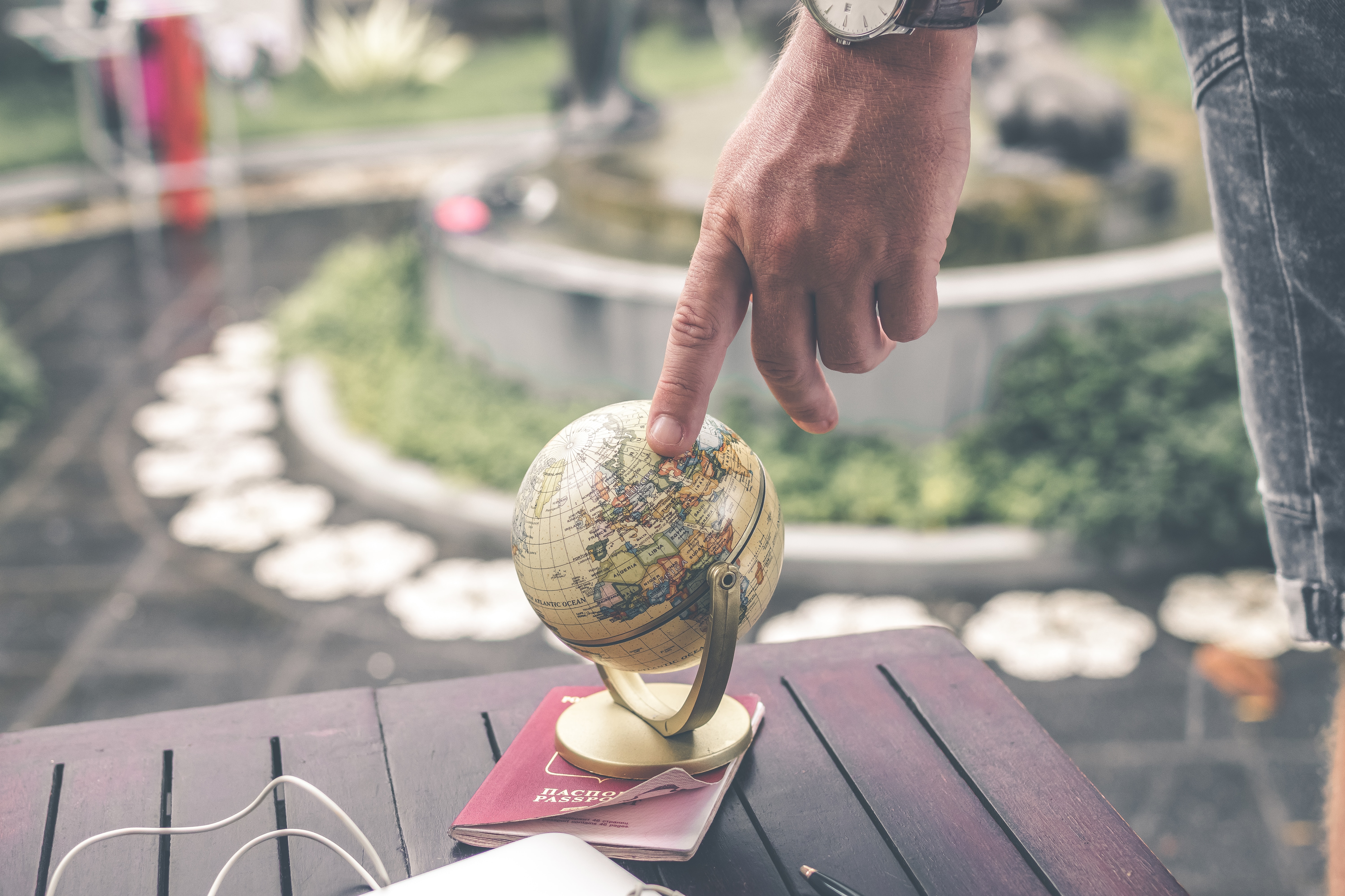 Person touching a small globe that is sitting on a park bench